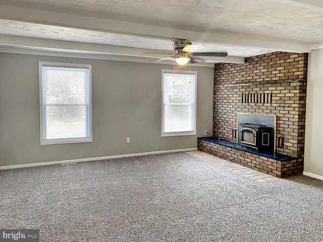 an empty room with windows and fireplace