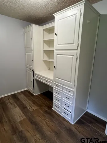 a view of an empty room with wooden floor and cabinet