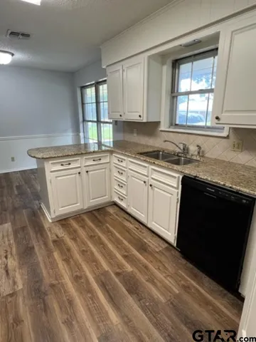a kitchen with granite countertop cabinets stainless steel appliances a sink and a window