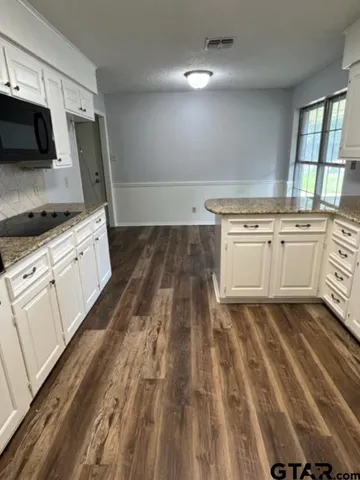 a kitchen with granite countertop a sink stove and microwave