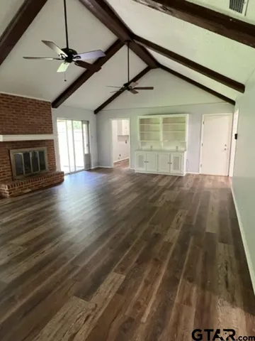 a view of an empty room with a window and wooden floor