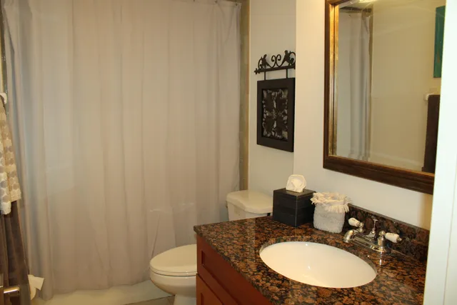 a bathroom with a granite countertop sink a toilet and a mirror