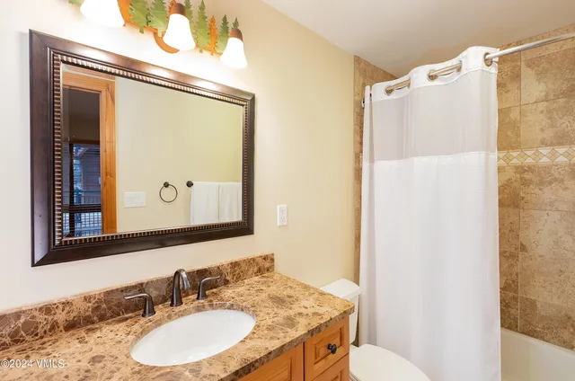 a bathroom with a granite countertop sink mirror vanity and toilet