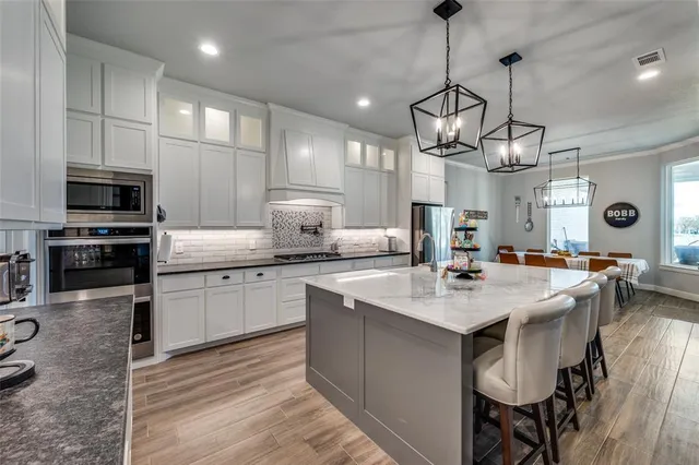 a kitchen with stainless steel appliances granite countertop a sink a stove and a refrigerator