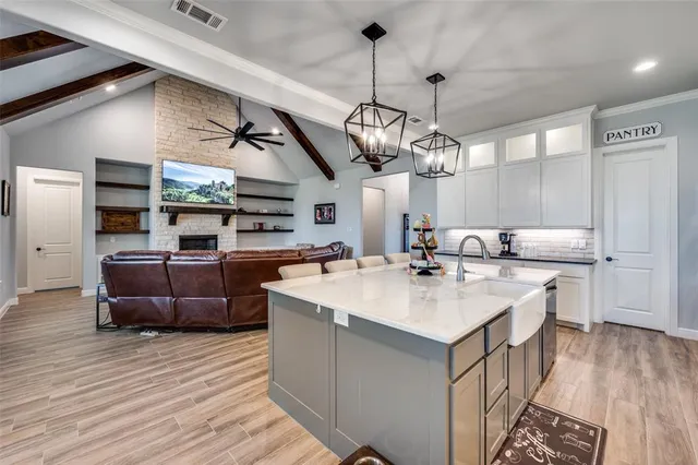 a large kitchen with a counter space a sink and living room view