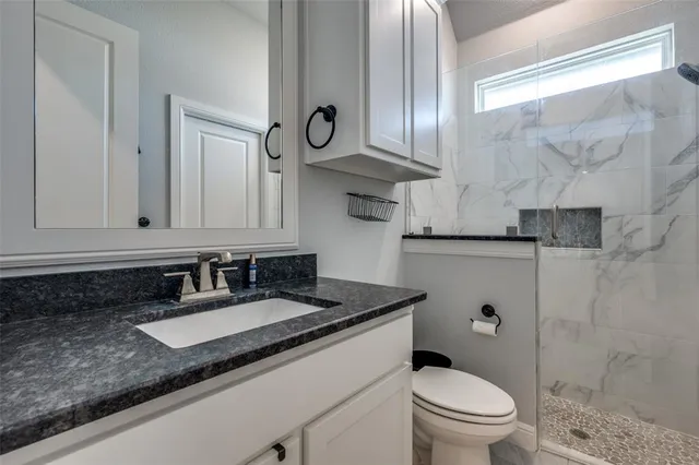 a bathroom with a granite countertop toilet sink and mirror