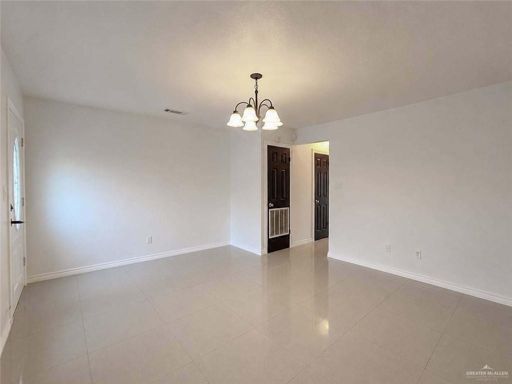2201 South Jackson Road, Unit 2I Pharr, TX 78577 - Photo 5 of 23 Spacious room featuring light-toned tile flooring, white baseboards, and a classic chandelier