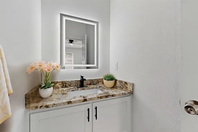a bathroom with a granite countertop sink and a mirror