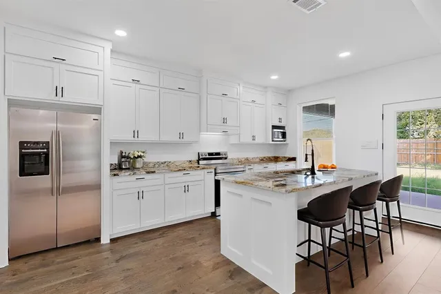 a kitchen with stainless steel appliances granite countertop a table chairs sink refrigerator and cabinets