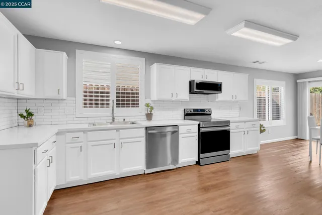 a kitchen with granite countertop white cabinets and black stainless steel appliances