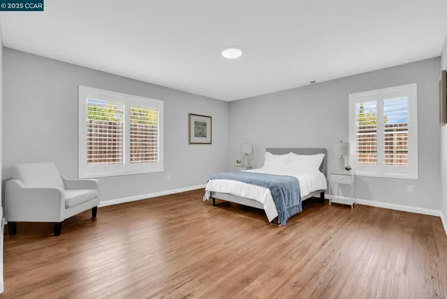 a spacious bedroom with a bed and a couch with wooden floor