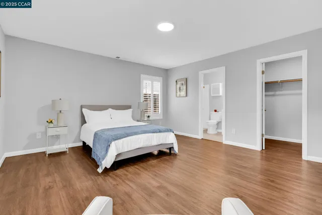 a spacious bedroom with a bed and wooden floor