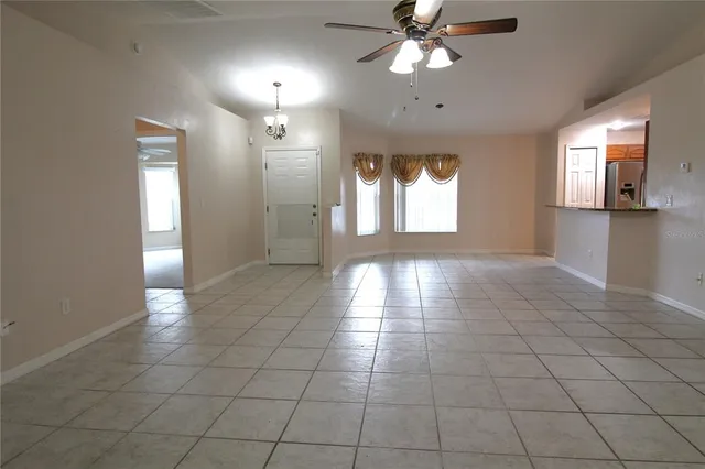 a view of an empty room with window and chandelier fan