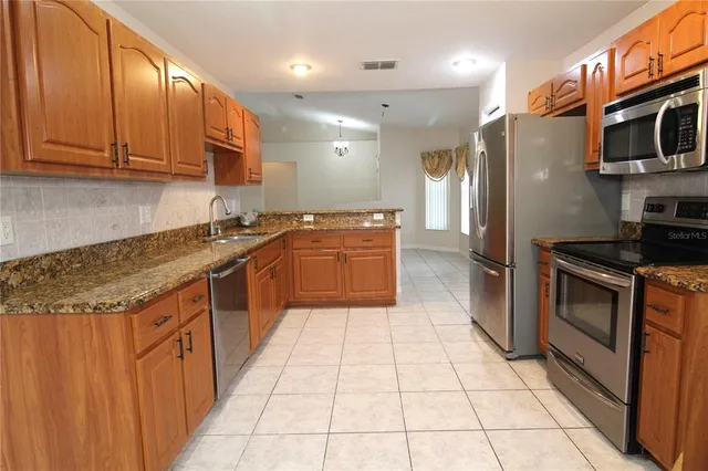 a kitchen with stainless steel appliances granite countertop a refrigerator and a stove top oven