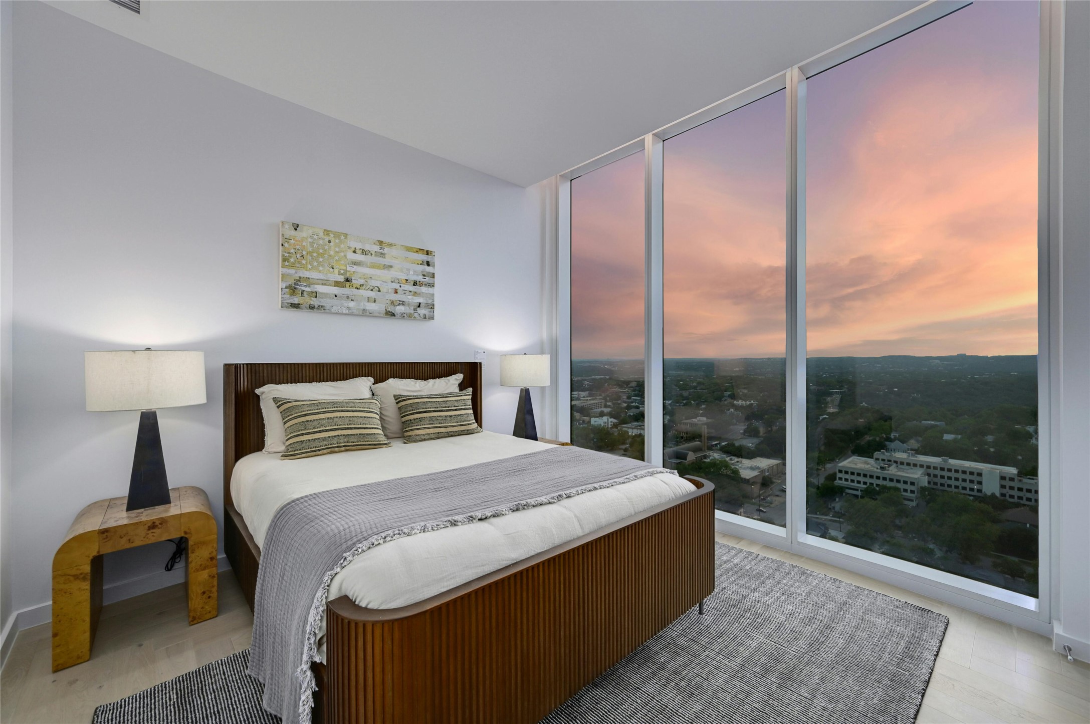 313 West 17th Street, Unit 2204 Austin, TX 78701 - Photo 14 of 40 Serene secondary bedroom with mesmerizing sunset views. Floor-to-ceiling windows frame a spectacular panorama of the city and surrounding landscape, creating a captivating backdrop for peaceful evenings. The tranquil space features warm wood accents, soft neutral tones, and thoughtful lighting that complements the natural glow of golden hour, offering the perfect retreat after a busy day.