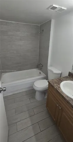 a bathroom with a granite countertop toilet a sink and bathtub