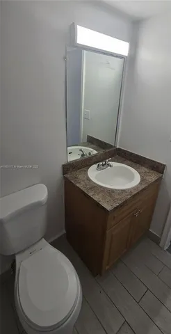 a bathroom with a granite countertop toilet a mirror and a sink