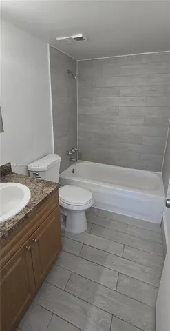 a bathroom with a granite countertop sink a toilet and bathtub