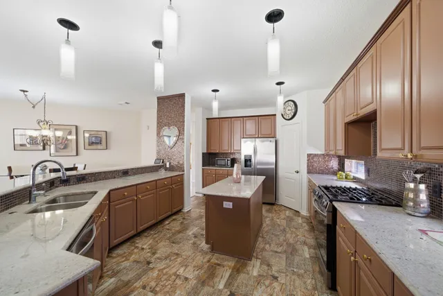 a large kitchen with granite countertop a sink counter space cabinets and stainless steel appliances