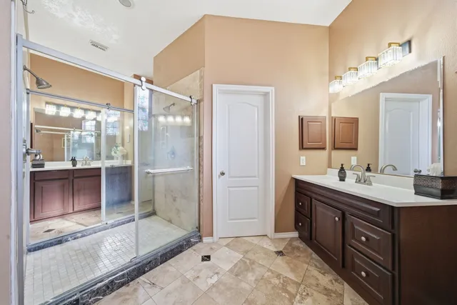 a bathroom with a double vanity sink mirror and shower