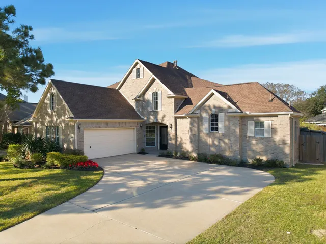 a view of a white house next to a yard with big trees