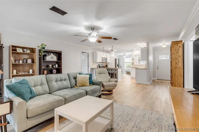 a living room with furniture kitchen view and a chandelier