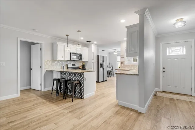 a kitchen with kitchen island granite countertop wooden floors and white cabinets
