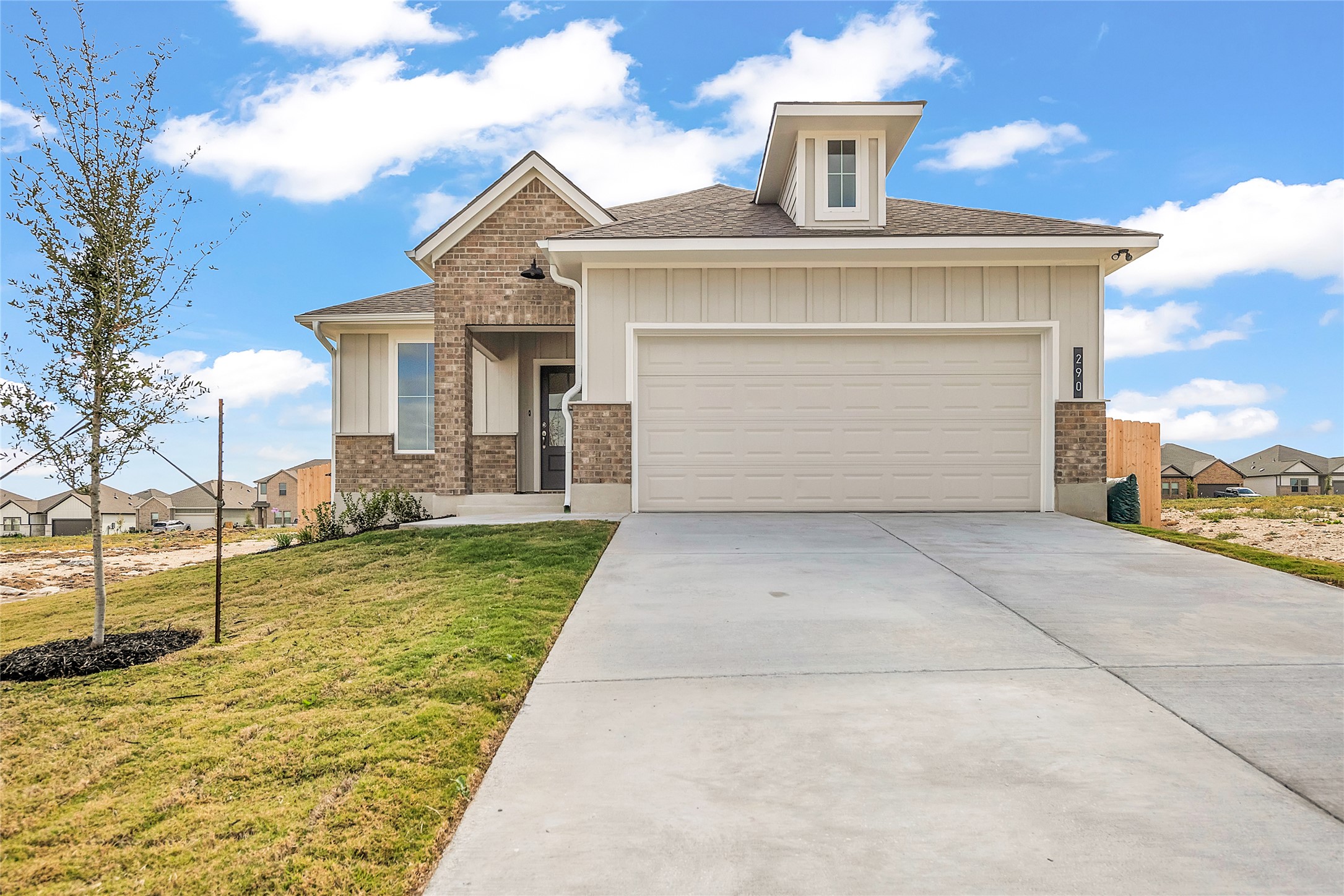 View of front of home with a front yard, a shingled roof, driveway, board and batten siding, and a garage