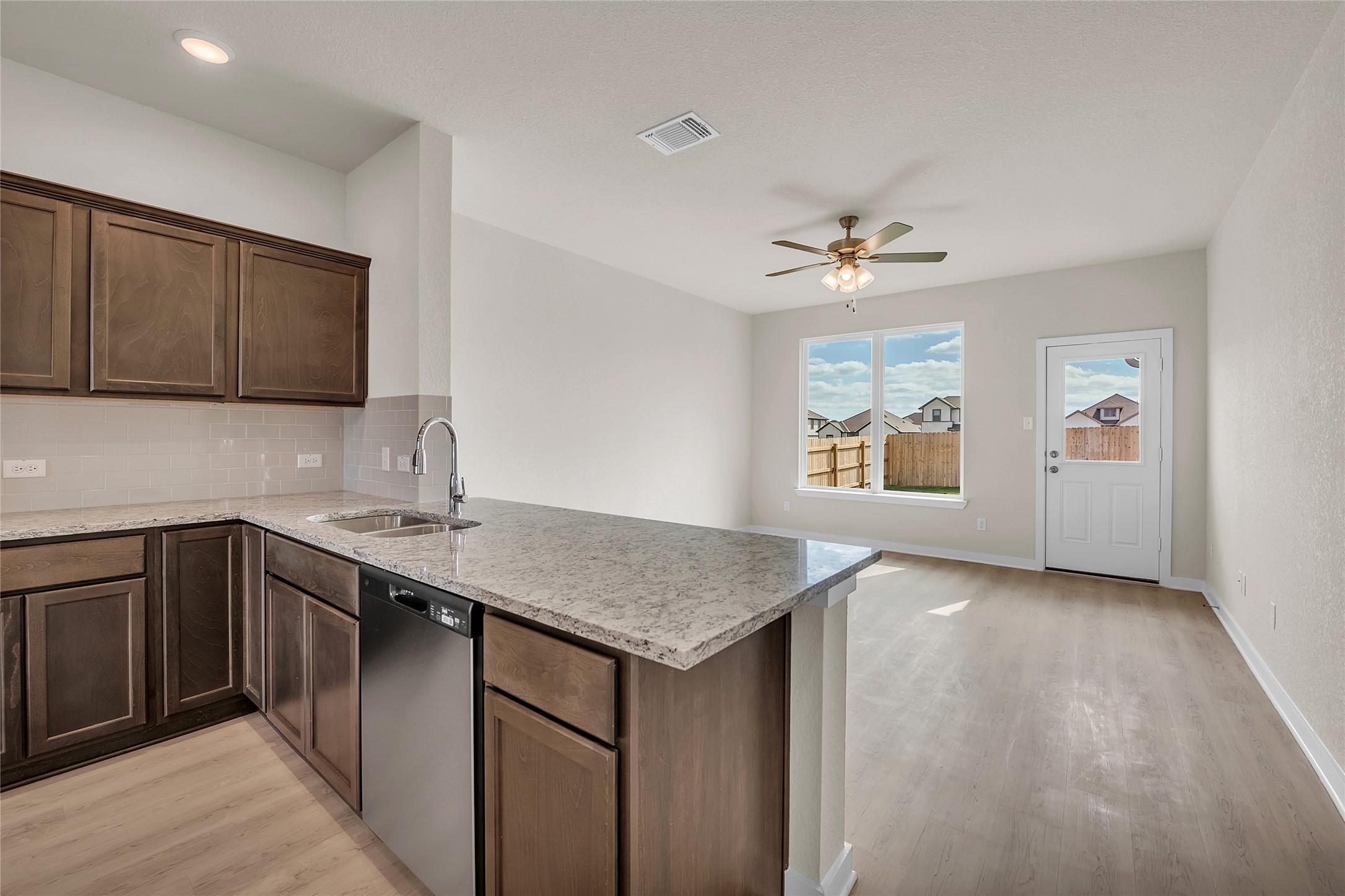 290 Boatright Boulevard Jarrell, TX 76537 - Photo 14 of 32 Kitchen with light stone counters, tasteful backsplash, stainless steel dishwasher, ceiling fan, and light wood finished floors