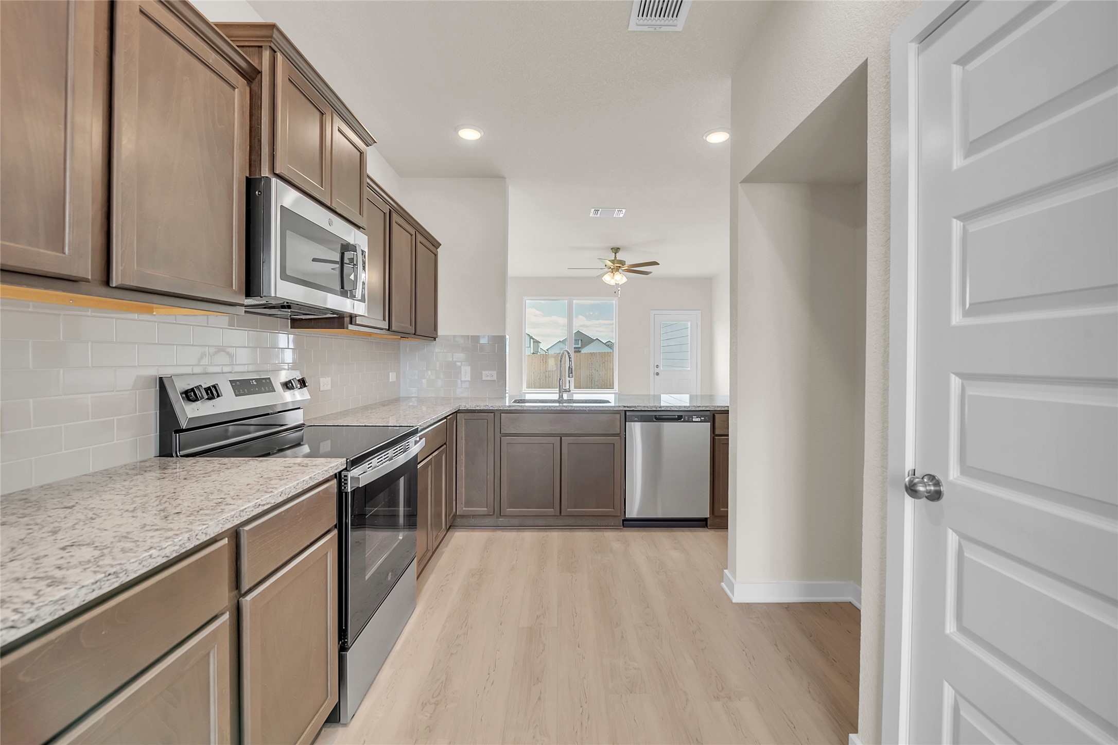 290 Boatright Boulevard Jarrell, TX 76537 - Photo 17 of 32 Kitchen featuring appliances with stainless steel finishes, recessed lighting, tasteful backsplash, light wood-style floors, and light stone countertops