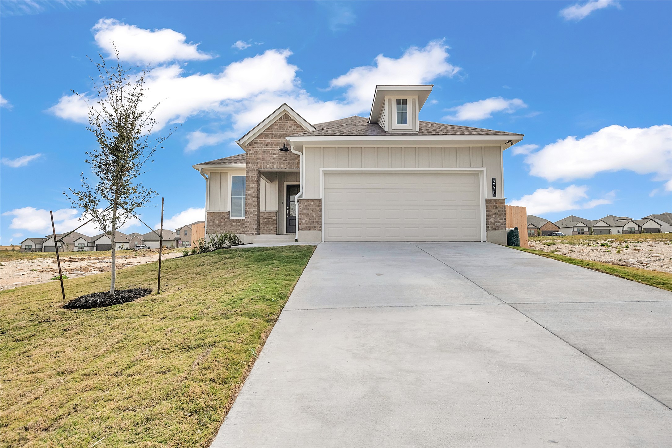 290 Boatright Boulevard Jarrell, TX 76537 - Photo 4 of 32 View of front of home with a front yard, driveway, a residential view, an attached garage, and brick siding