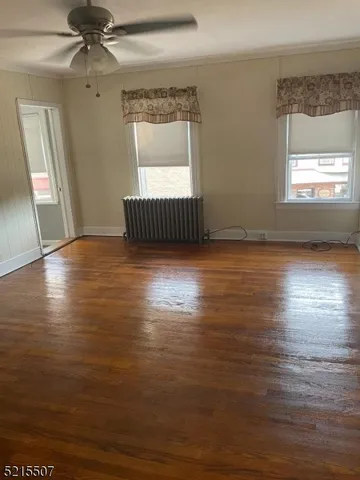 an empty room with wooden floor chandelier and windows
