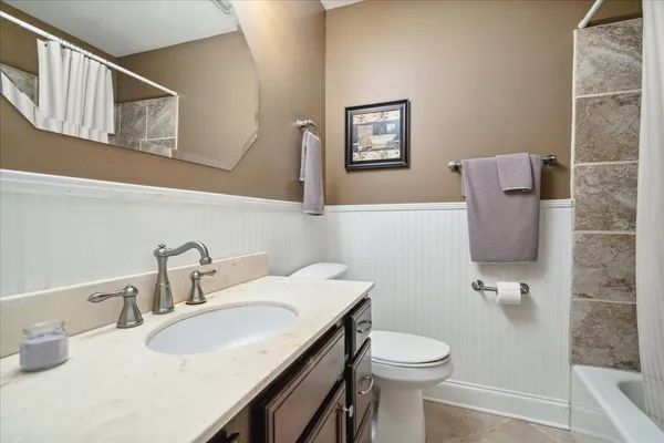 a bathroom with a granite countertop sink and a toilet