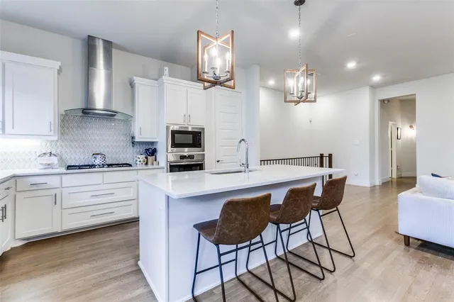 a kitchen with stainless steel appliances kitchen island granite countertop a table chairs sink and cabinets