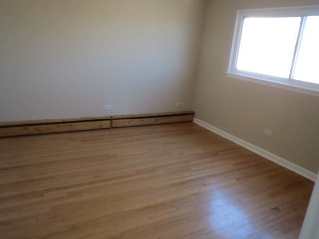 7858 Rutherford Avenue, Unit 2A Burbank, IL 60459 - Photo 4 of 10 a view of an empty room with wooden floor and a window