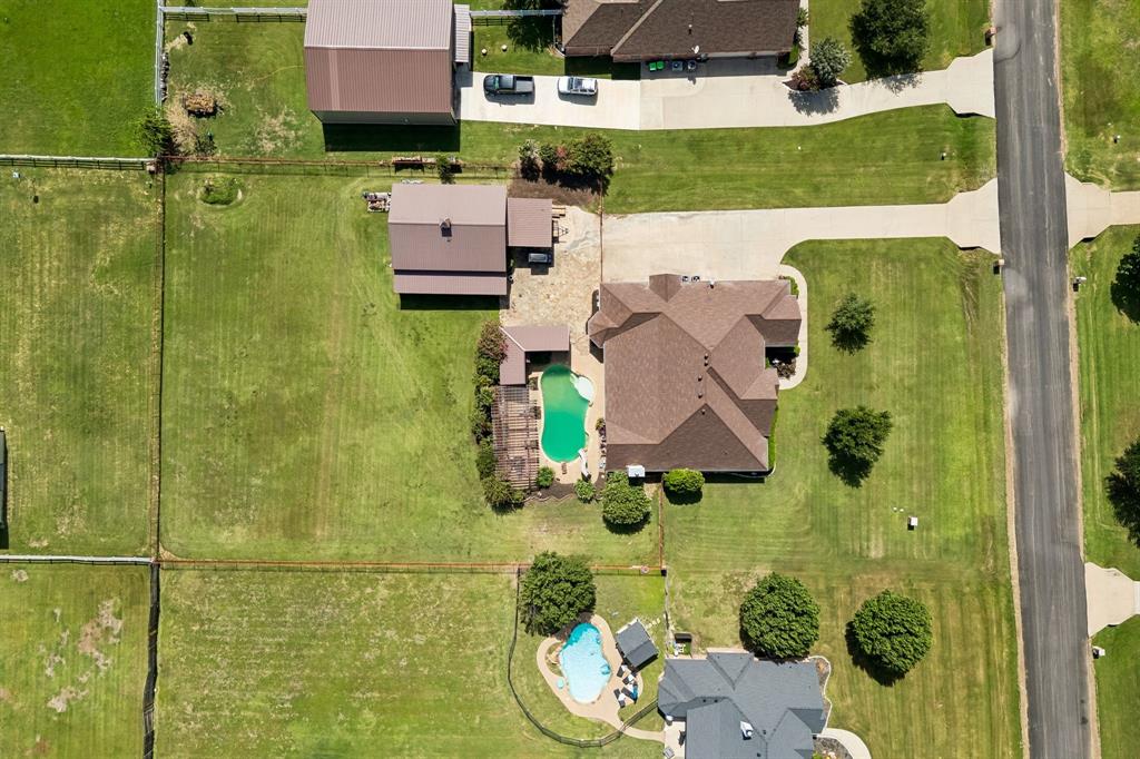 317 Singing Quail Trail Haslet, TX 76052 - Photo 30 of 32 Expansive property featuring a brown-roofed residence, a large swimming pool, an extensive paved patio, and a separate outbuilding with a metal roof
