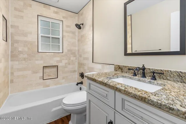 a bathroom with a granite countertop sink toilet mirror and bathtub