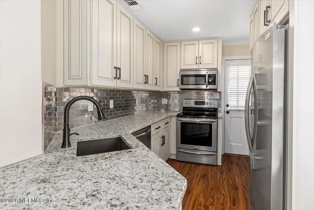 a kitchen with stainless steel appliances granite countertop a stove a sink and a refrigerator