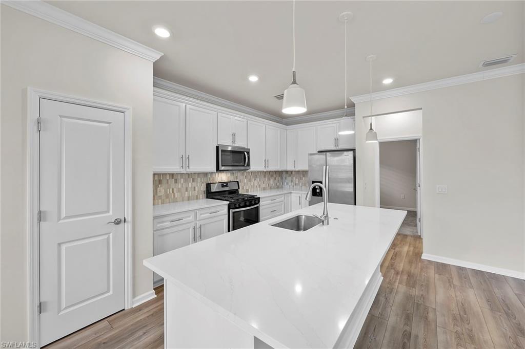 2236 Yellowfin Circle Naples, FL 34114 - Photo 13 of 39 a kitchen with white cabinets and stainless steel appliances