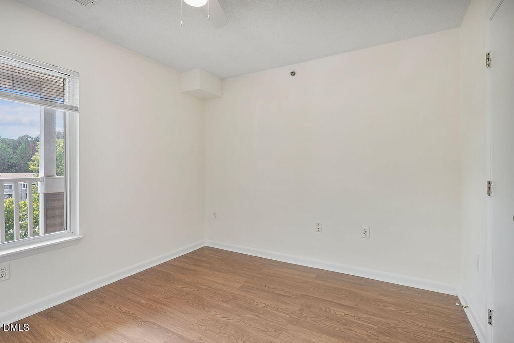 1411 Collegiate Circle, Unit 302 Raleigh, NC 27606 - Photo 32 of 43 a view of an empty room with wooden floor and a window