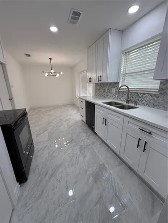a kitchen with granite countertop a sink a stove and cabinets