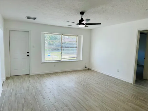 a view of an empty room with wooden floor and a window