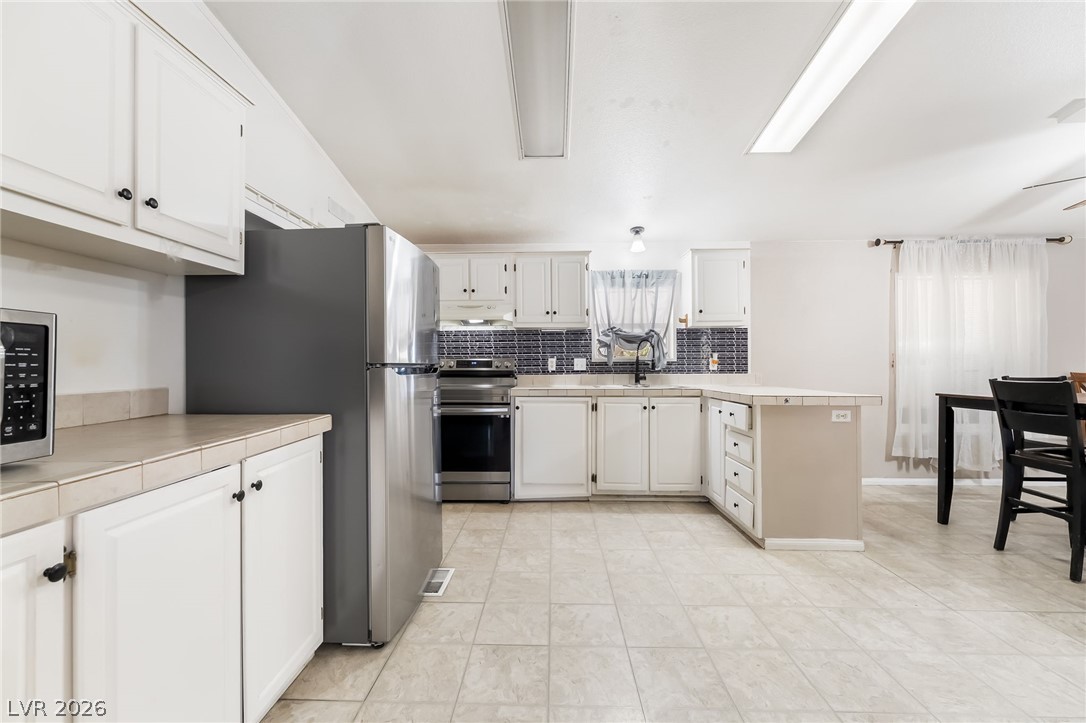 1551 West Wilson Road Pahrump, NV 89048 - Photo 17 of 68 White cabinetry paired with durable tile flooring defines this functional kitchen layout.