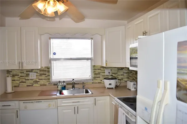 a kitchen with stainless steel appliances white cabinets a sink a window and a refrigerator