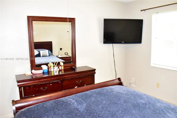 a living room with a flat screen tv on the dresser and a bookshelf