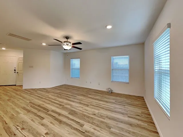 a view of empty room with wooden floor and fan