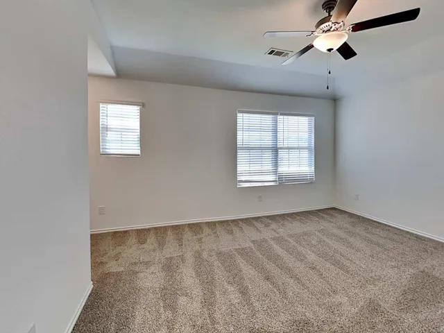 an empty room with windows and fan