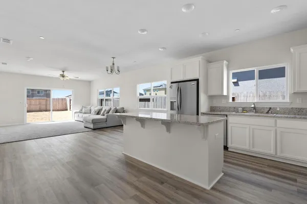 a living room with stainless steel appliances granite countertop furniture and a wooden floor
