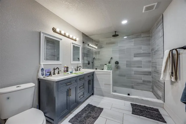 a bathroom with a granite countertop sink a toilet and shower