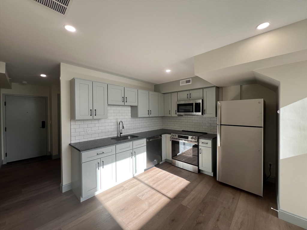 a large kitchen with cabinets stainless steel appliances and wooden floor